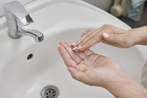 Caucasian woman practicing proper hygiene by washing hands over a sink