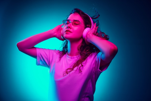 Caucasian woman's portrait isolated on blue  background in multicolored neon light.