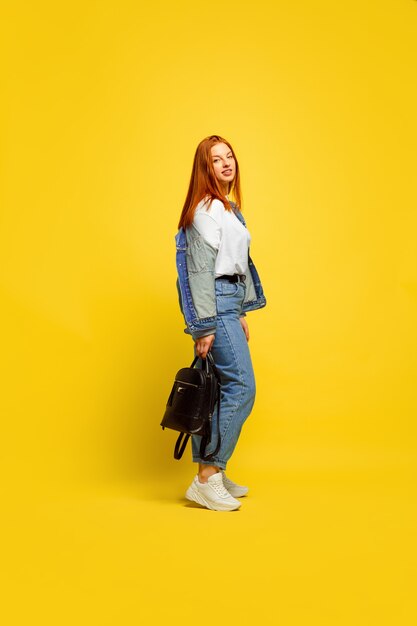 Caucasian woman's portrait on yellow background.