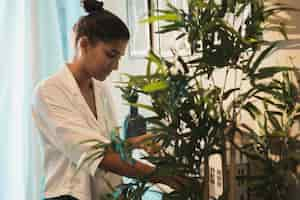 Free photo caucasian woman taking care of home plants