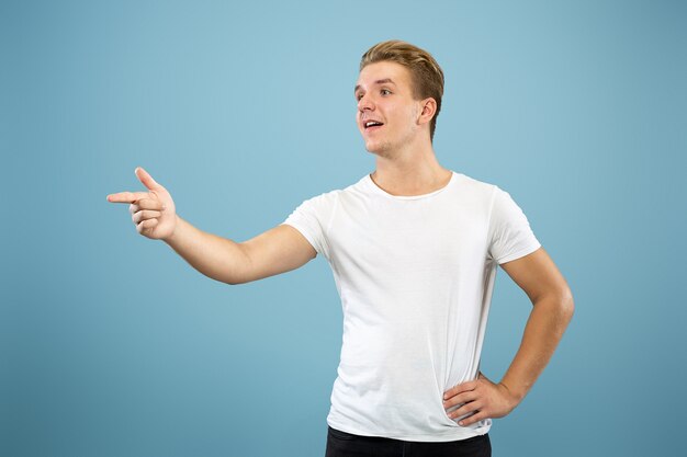 Caucasian young man's half-length portrait on blue studio