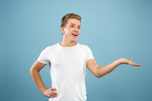 Caucasian young man's half-length portrait on blue studio