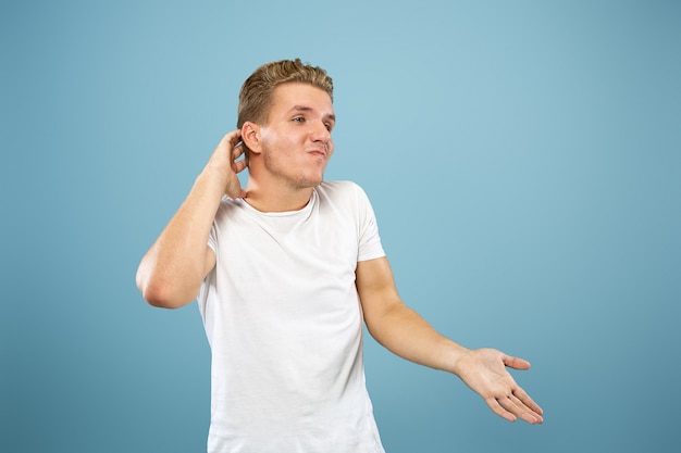 Caucasian young man's half-length portrait on blue studio