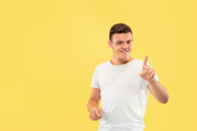 Caucasian young man's half-length portrait on yellow studio