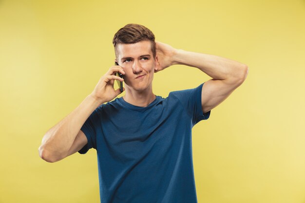 Caucasian young man's half-length portrait on yellow studio