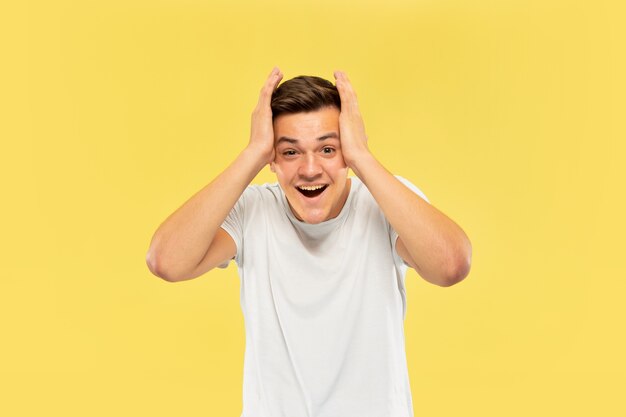 Caucasian young man's half-length portrait on yellow studio