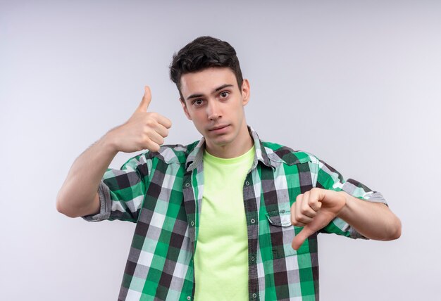 caucasian young man wearing green shirt his thumb up other down on isolated white wall