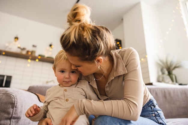 Free Photo caucasian young mother with her little son spend time together sitting on sofa at weekend loving motherhood concept