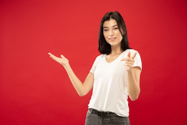 Caucasian young woman's half-length portrait on red studio