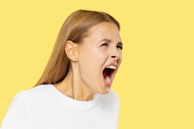 Free Photo caucasian young woman's half-length portrait on yellow studio background. beautiful female model in white shirt