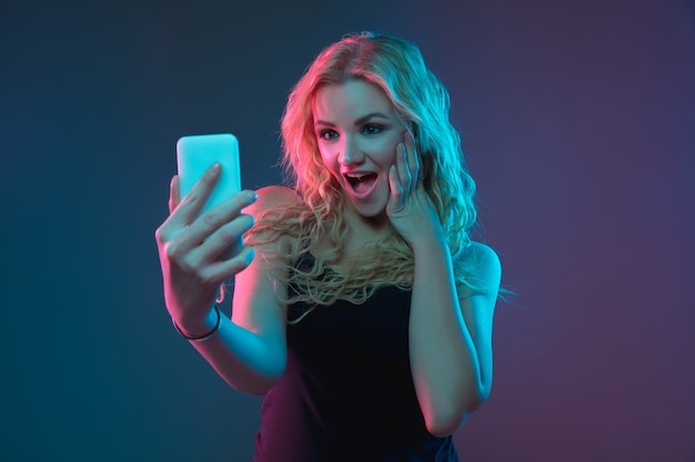 Free Photo caucasian young woman's portrait on gradient background in neon light. beautiful female model with unusual look. concept of human emotions, facial expression, sales, ad. making selfie, bet, purchases.