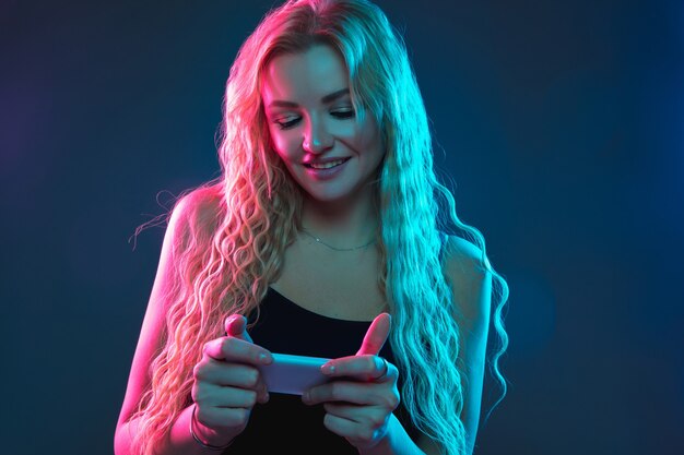 Caucasian young woman's portrait on gradient in neon light