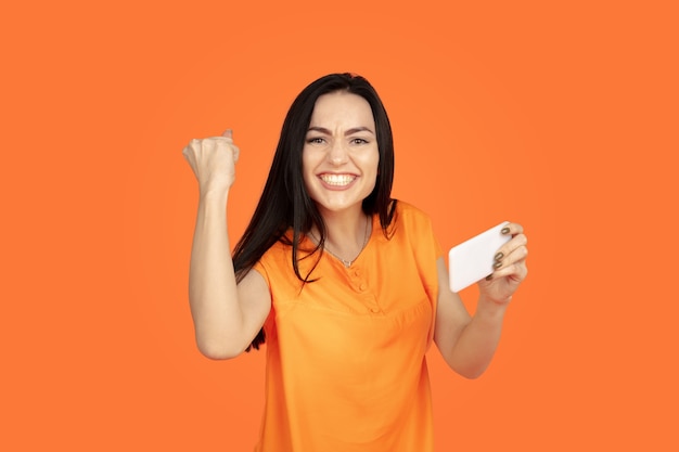 Caucasian young woman's portrait on orange background