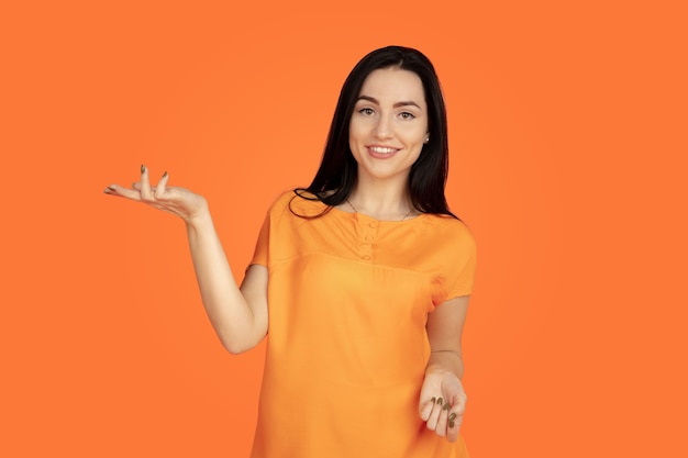 Caucasian young woman's portrait on orange background