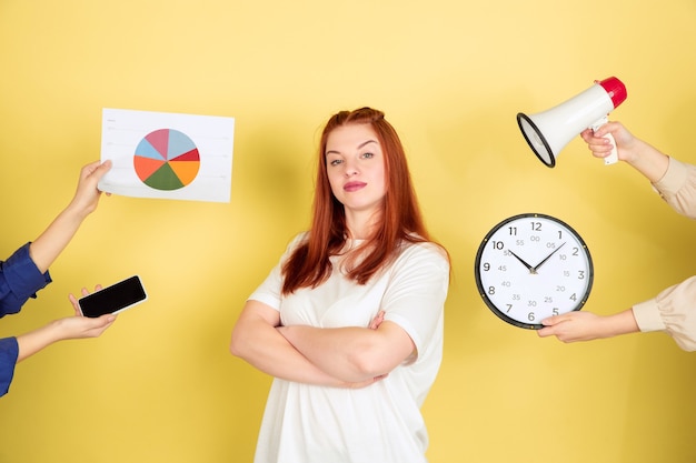 Caucasian young woman's portrait on yellow background, too much tasks