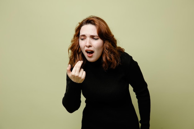 Caughing with closed eyes young ill female isolated on green background