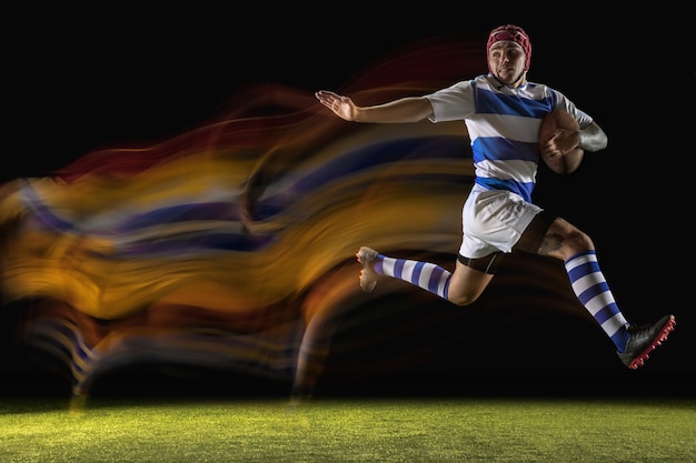 Free photo caught in important moment. one caucasian man playing rugby on the stadium in mixed light.