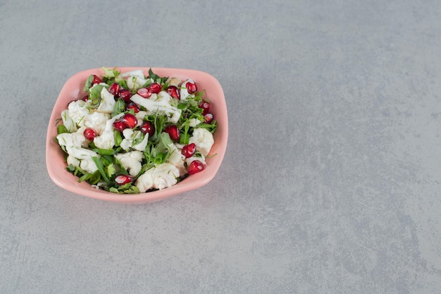 Cauliflower salad in the plate with pomegranate seeds and herbs.