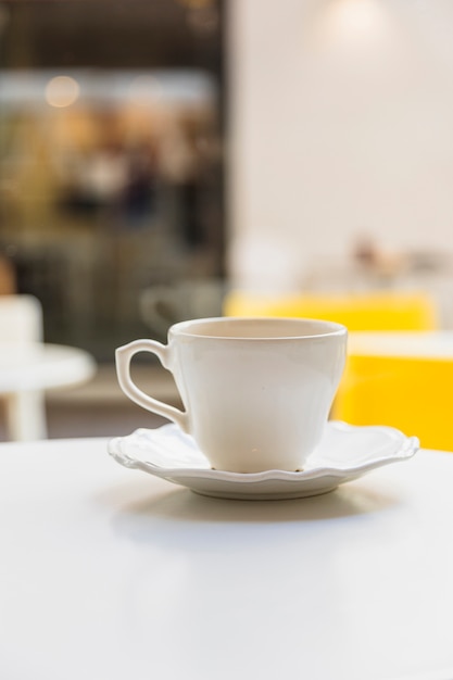 Free photo ceramic cup and saucer on white table against blur background