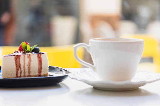 Free photo ceramic cup and saucer with delicious cake slice on white surface