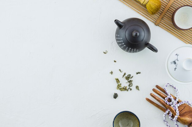 Ceramic tea pot and cups with herbs isolated on white backdrop