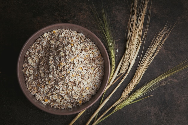 Free photo cereal product in a bowl with wheat top view on a dark brown