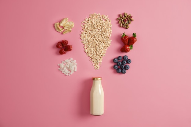 Cereals with dried apples, dates, cashew, pistachio around bottle with milk