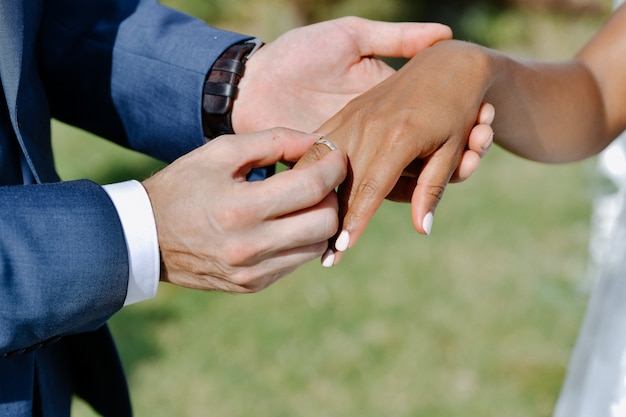 Ceremony of putting the wedding ring on the bride's finger outdoors