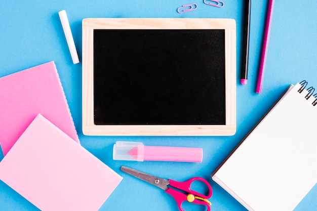 Chalk board and school tools on colored surface