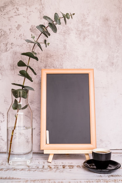 Free Photo chalkboard beside cup and branch in bottle 