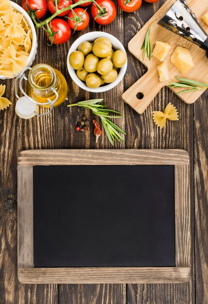 Chalkboard beside fusilli with olives and vegetables