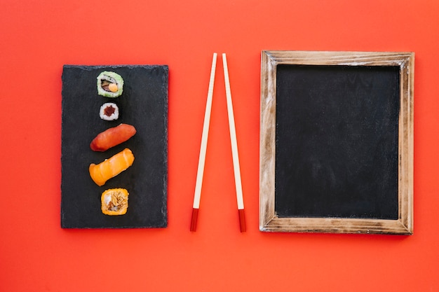 Free photo chalkboard and chopsticks near rolls