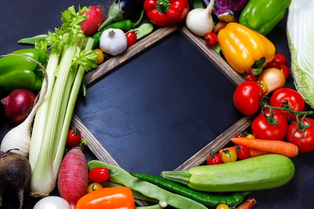 Chalkboard with different colorful healthy vegetables on dark background