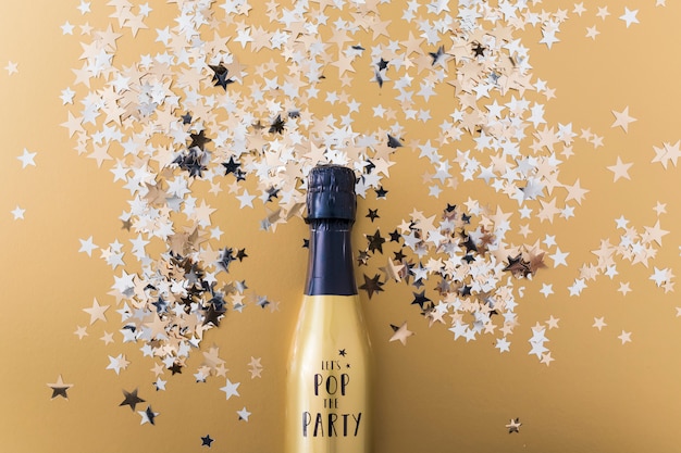 Free photo champagne bottle with spangles on table