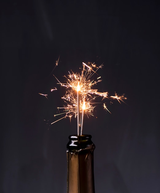 Free Photo champagne bottle with sparklers on black background