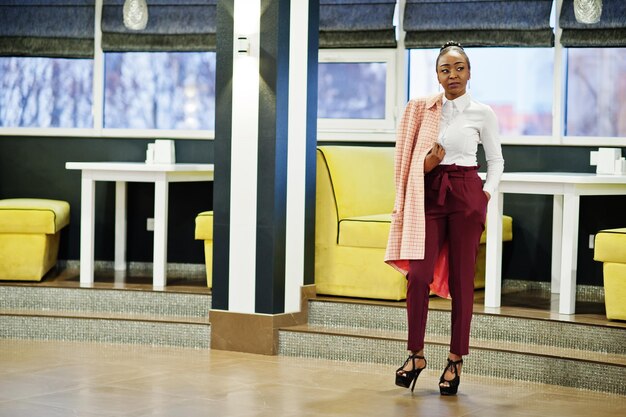 Charming african american woman in formal wear posing at restaurant