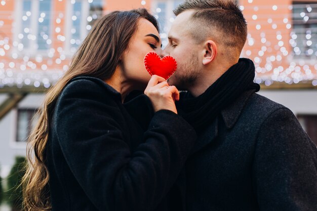 Charming couple kissing while posing with hear