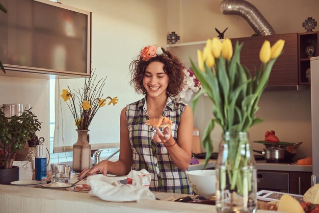 Charming curly Hispanic girl makes pizza while cooking in her kitchen.