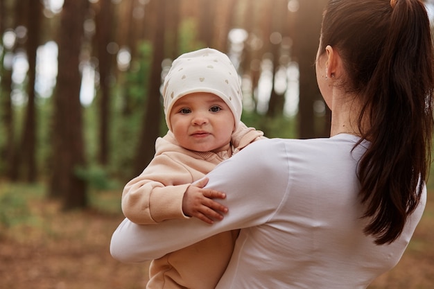 Free photo charming cute little infant baby in mommy's hands looking at front