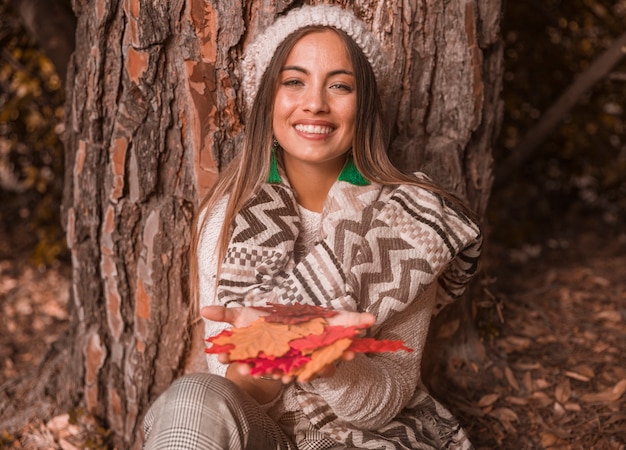 Free photo charming female with autumn leaves near tree