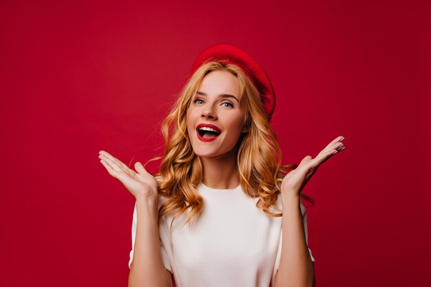 Charming french young woman enjoying photoshoot. Indoor shot of cheerful white girl in french beret.