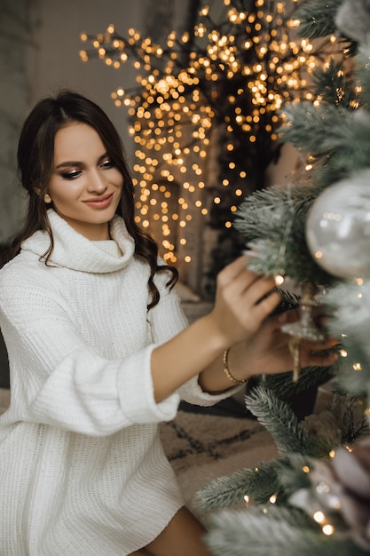 Charming girl is hanging a toy on a Christmas tree