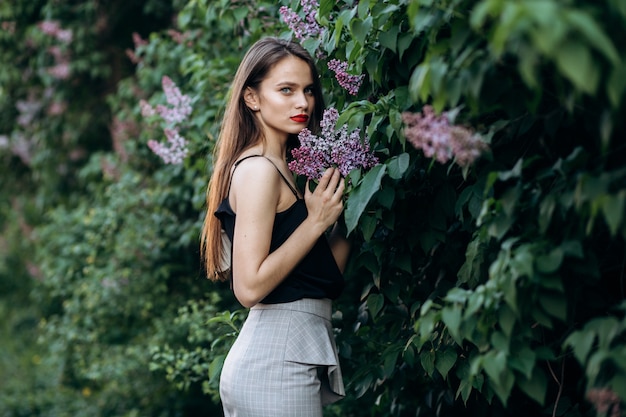 Free photo the charming girl stands near bushes with flowers