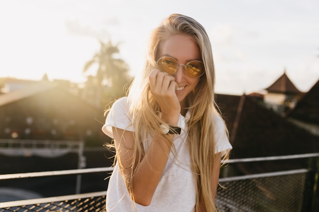 Charming girl in wristwatch posing with shy smile on sky background.