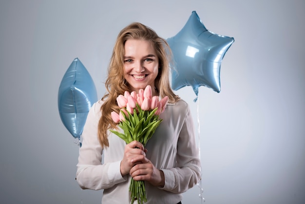 Free photo charming glad female with bouquet of flowers and balloons