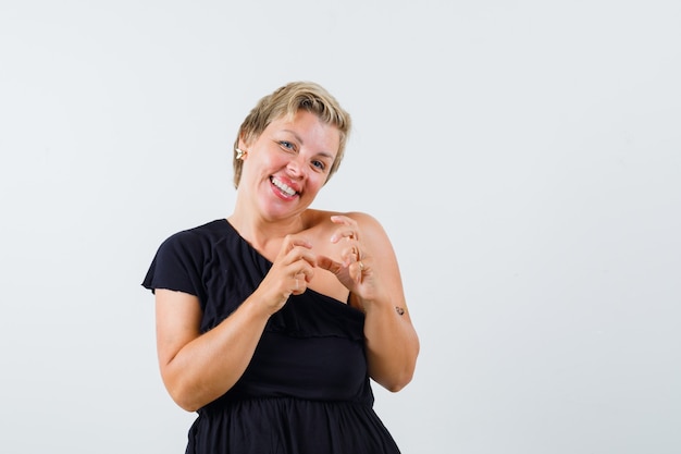 Charming lady in black blouse holding something while smiling and looking happy 