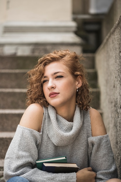 Charming lady with short curly hair holding books