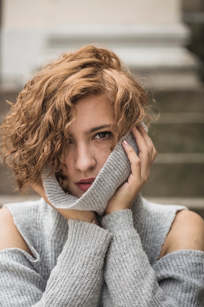 Free photo charming lady with short curly hair holding sweater's collar