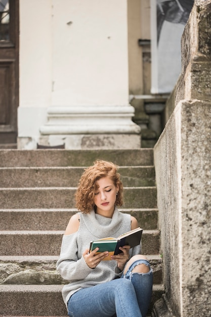 Free photo charming lady with short curly hair reading book