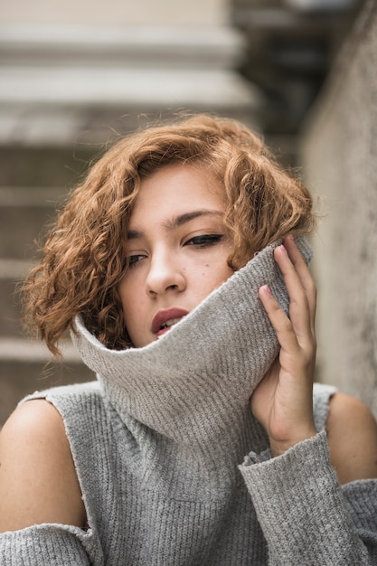 Charming lady with short tufty hair holding raised sweater's collar